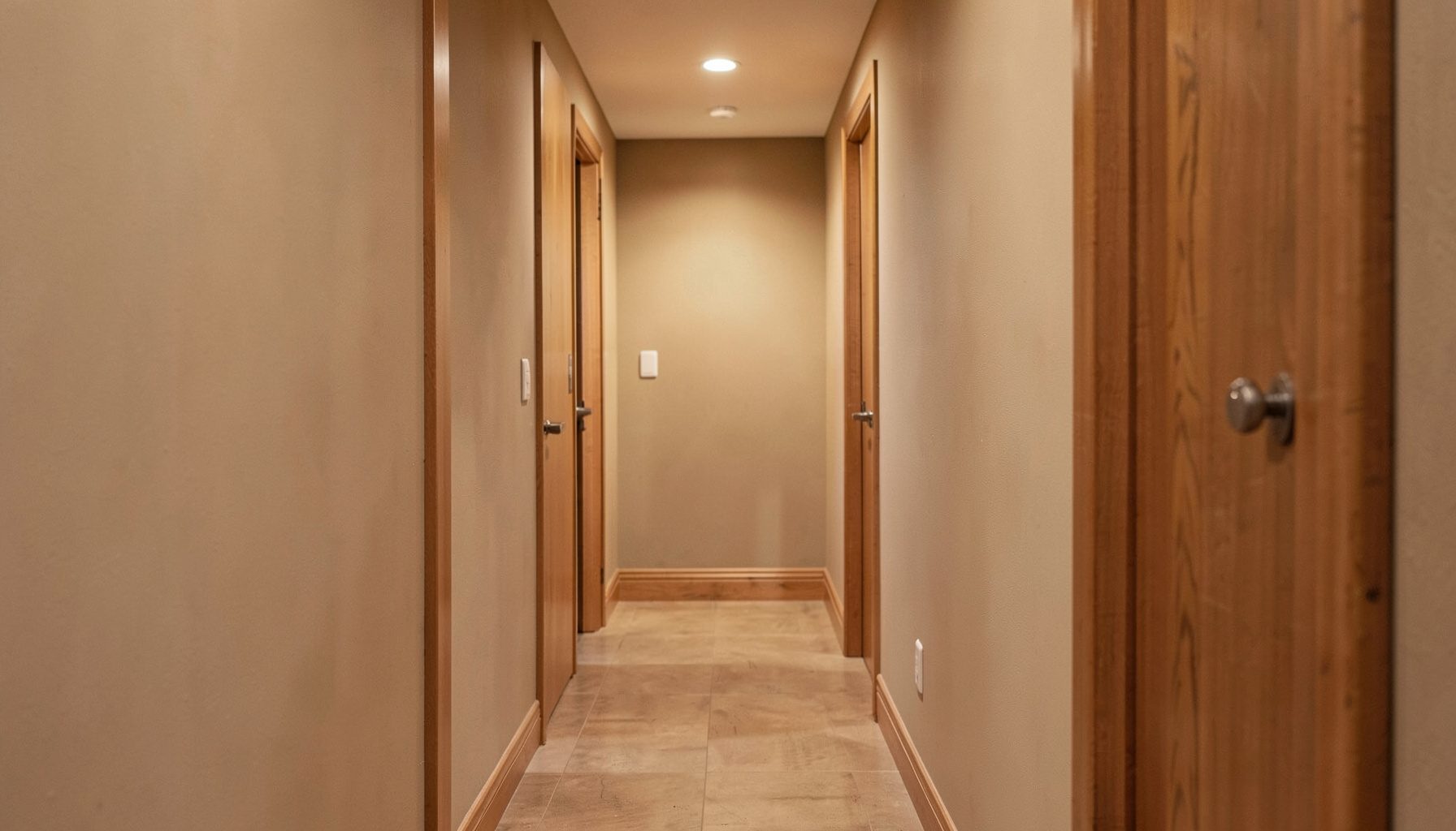 Softly lit interior hallway with warm wood tones and a neutral wall, conveying a calm residential atmosphere